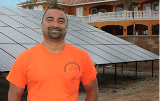Cesar Mendoza in front of solar panels he's installed