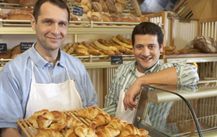 two men posing in their bakery